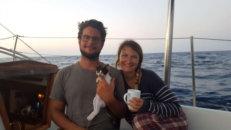 a couple and their cat on a sailboat