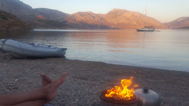 a dinghy and sailboat on a greek beach