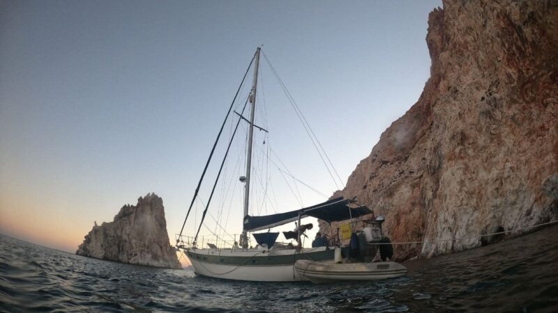 a sailboat at anchor by some pretty rocks