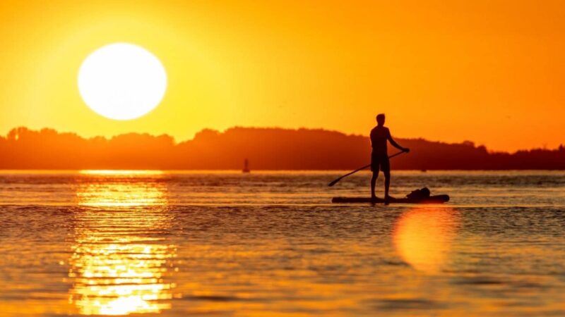 a man paddle boarding into the sunset