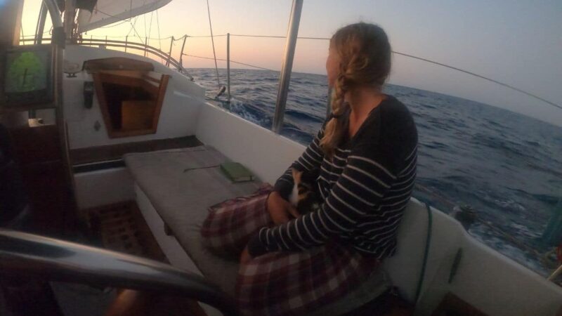 a girl and her cat on a sailboat at sea