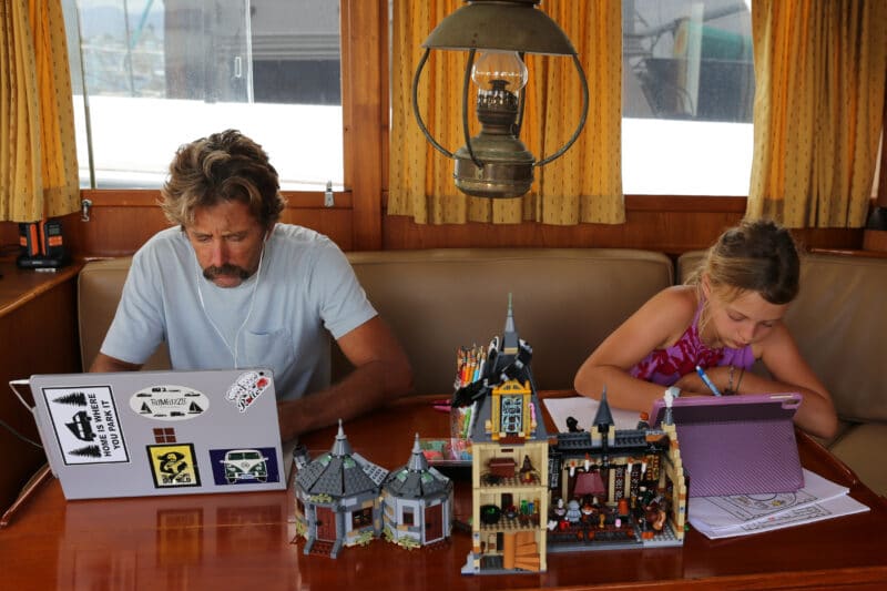 A man making money while living on a trawler by trading on a laptop.