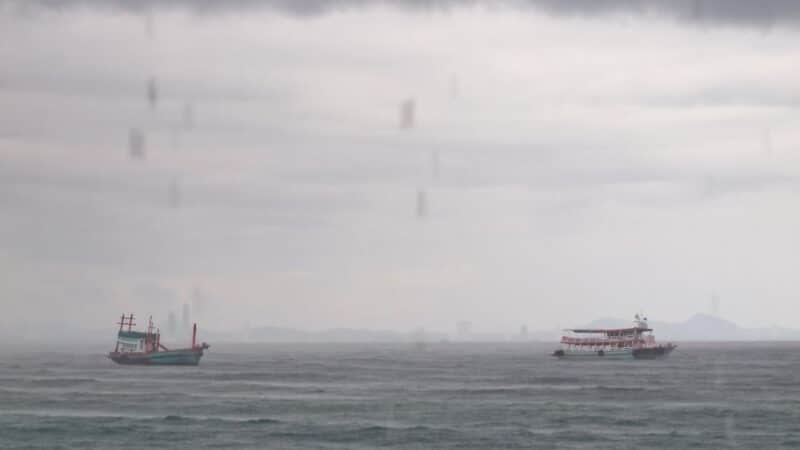 two boats out sailing in the rain and wind