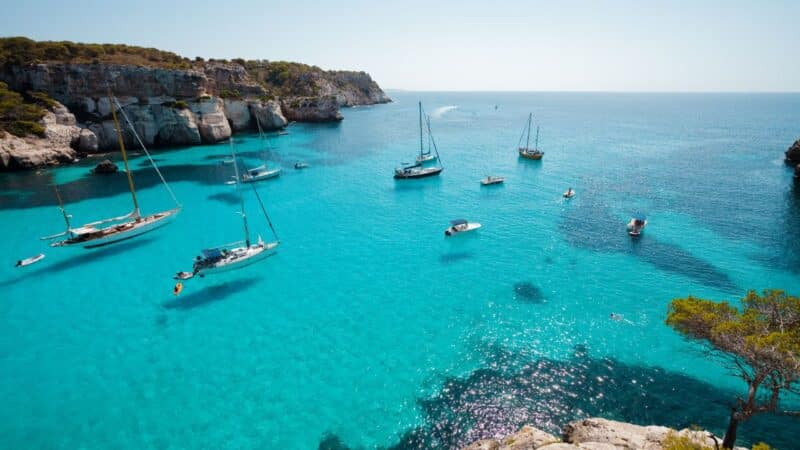 loads of sailboats anchored in a pretty bay at the best time to visit spain