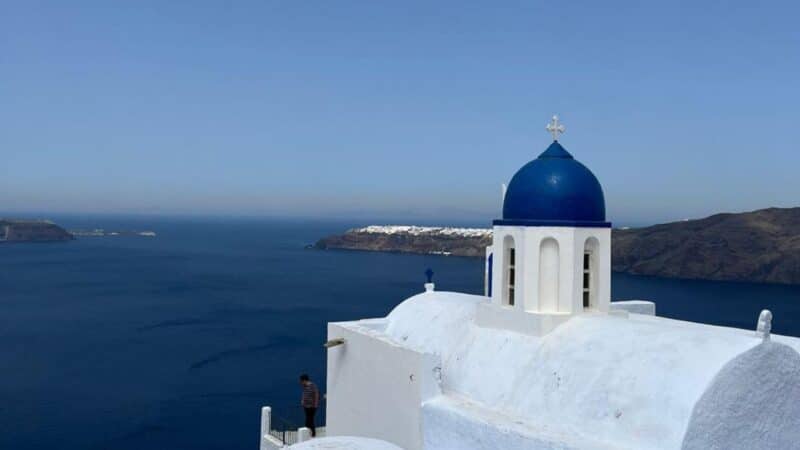 a blue domed church with sea views behind it