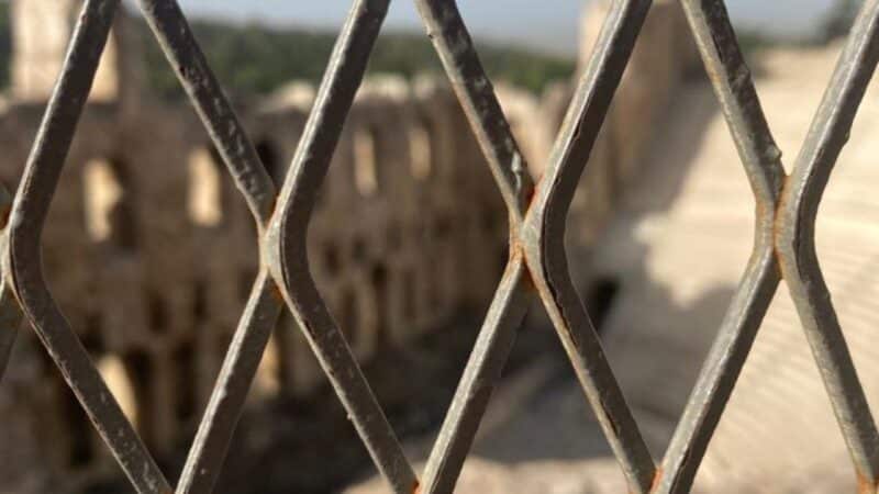 a view of some ancient ruins in athens through a fence