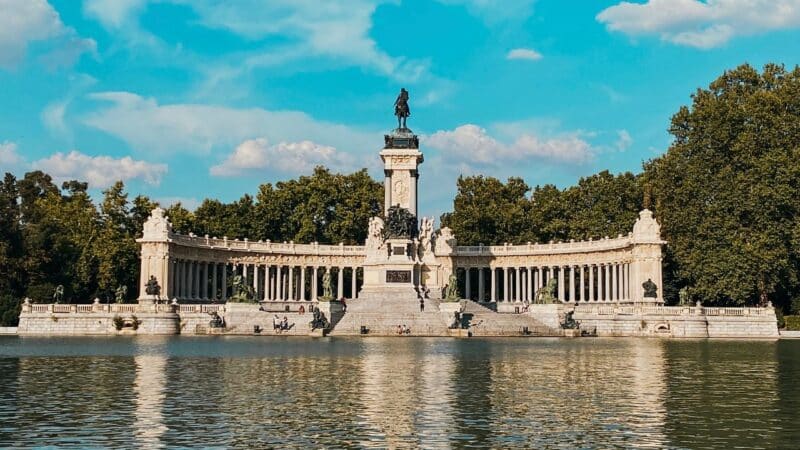 a lake with a statue behind in madrid