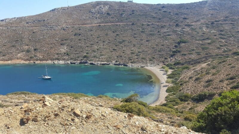 a beautiful greek harbour with a sailboat anchored there