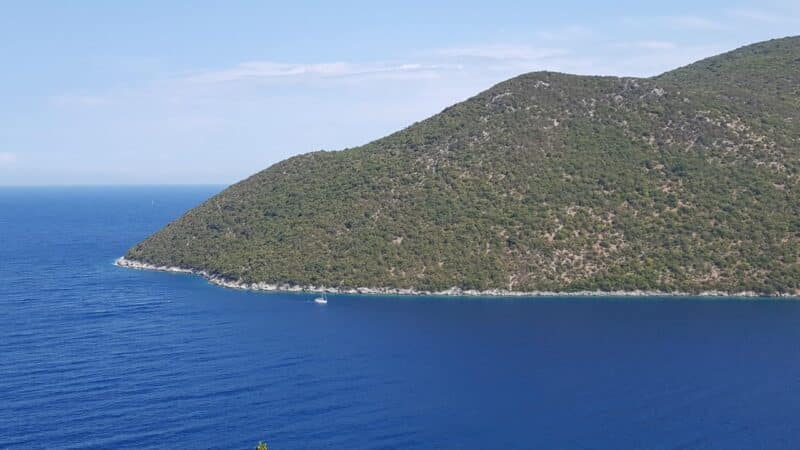 a mountain leading down to blue sea