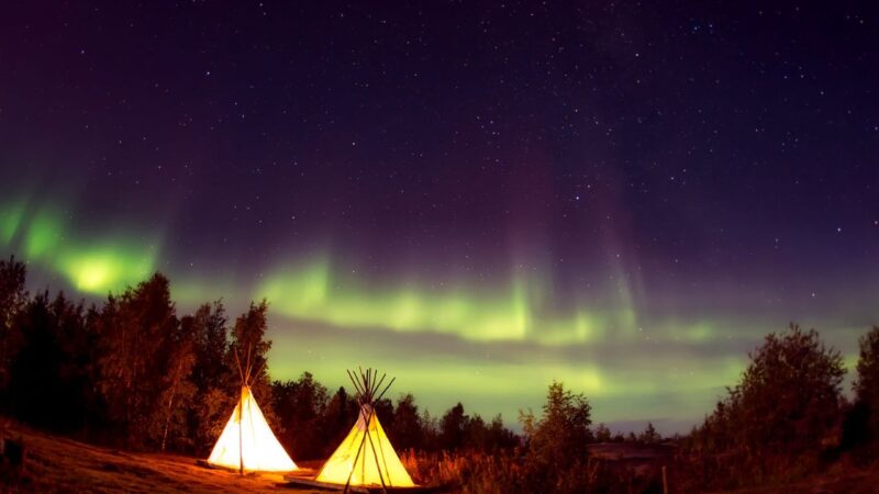 some tipis against the backdrop of the northern lights in iceland